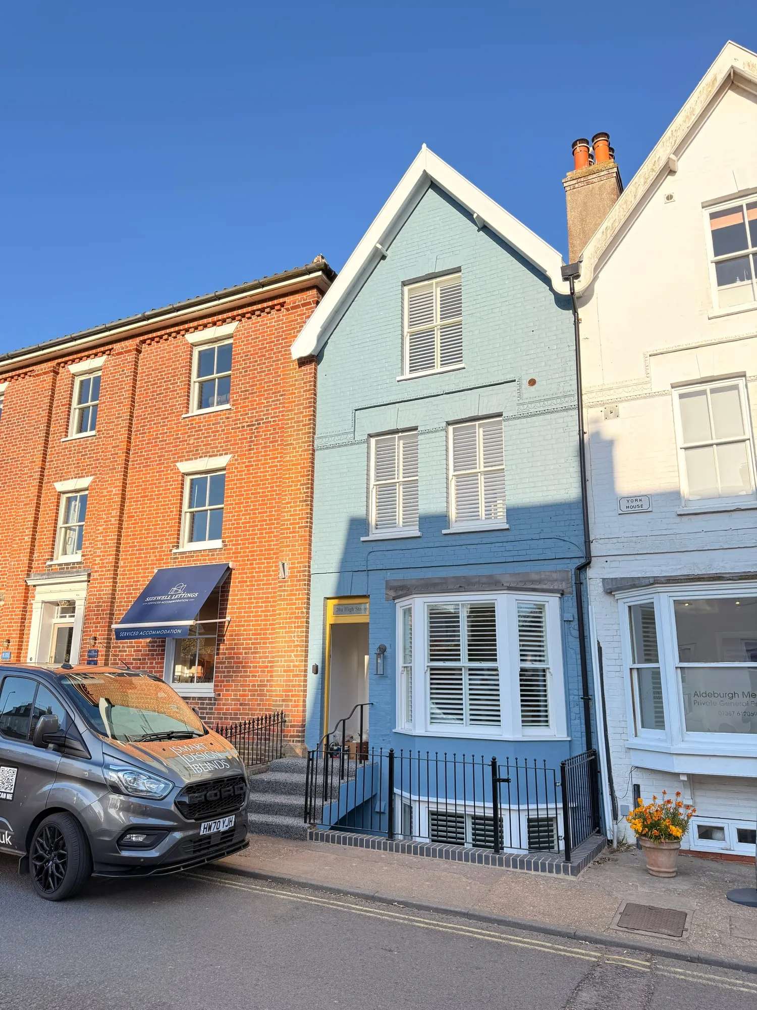 Duck-egg-blue Aldeburgh townhouse with white plantation shutters fitted to the bay frontage and Smart Design Blinds van outside