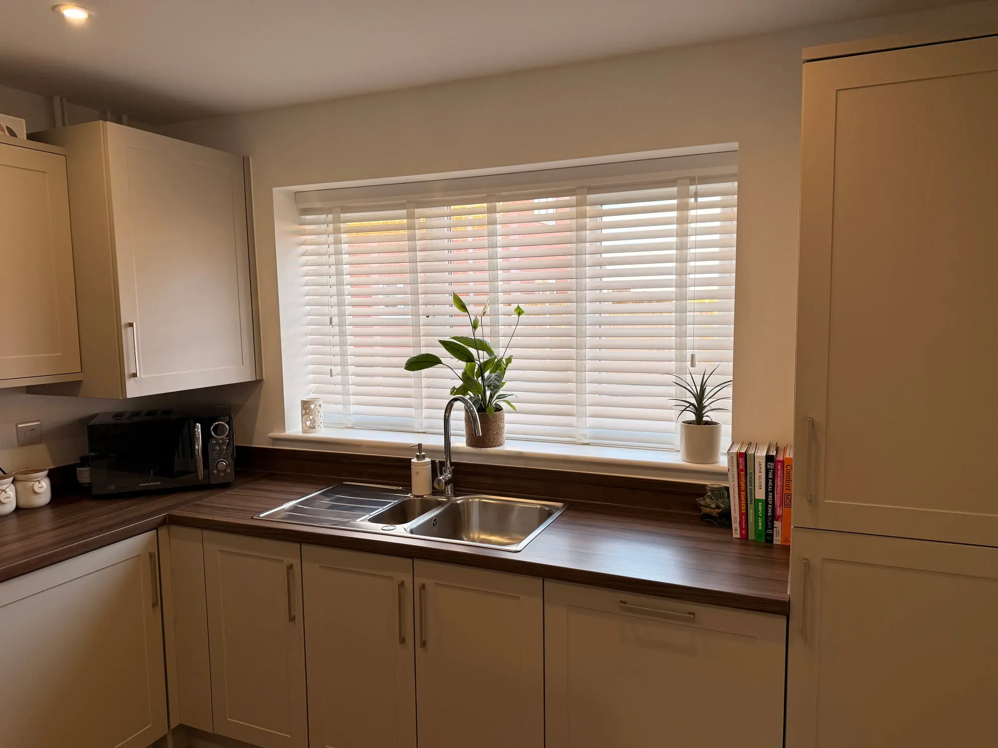 White wood venetian blinds with tape in a modern cream-Shaker kitchen with walnut worktop in a Suffolk new-build